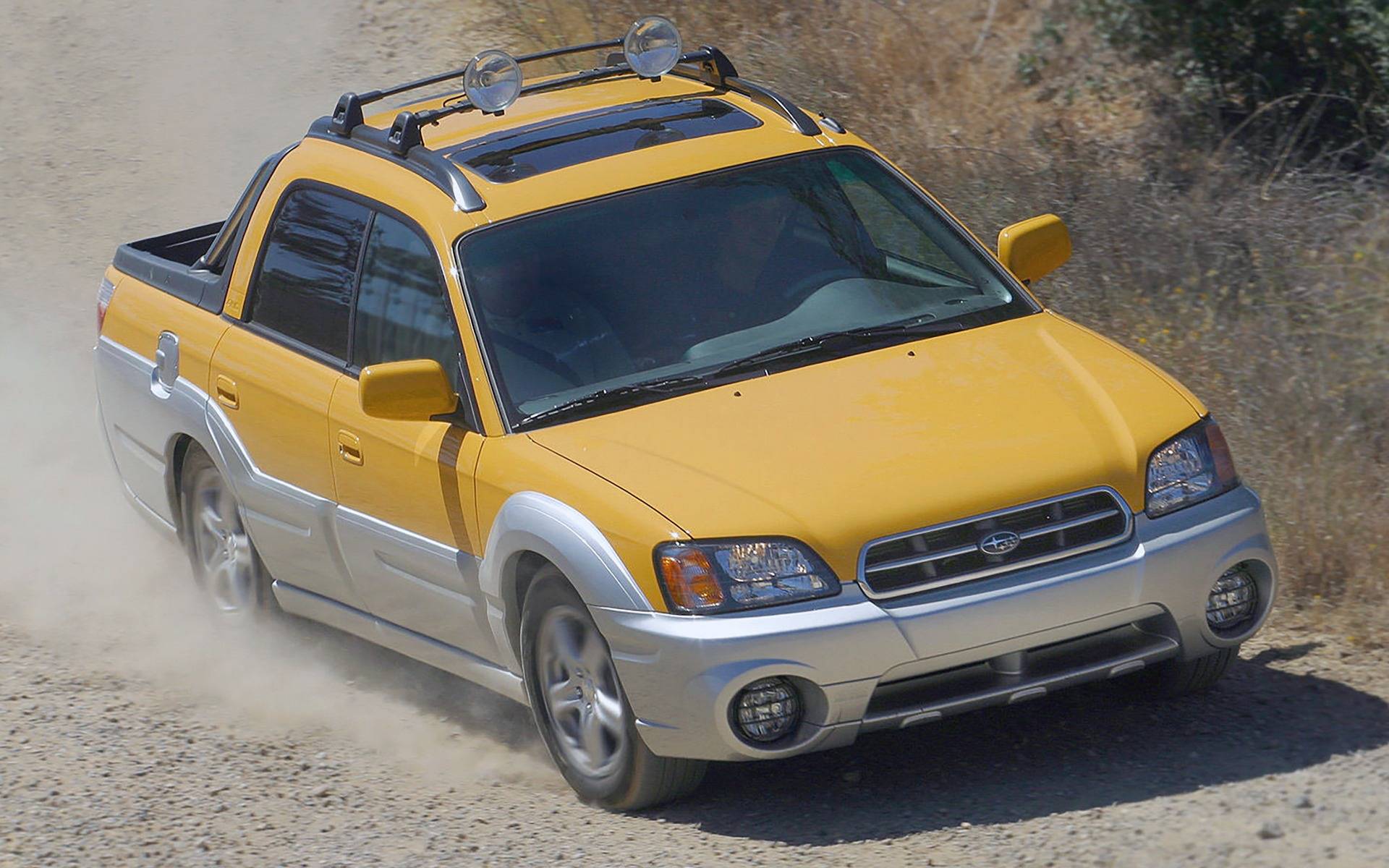 Žlutý nákladní vůz Subaru Baja jedoucí po polní cestě