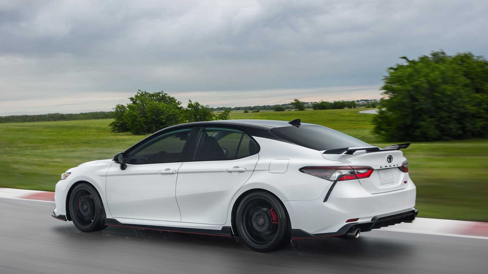rear 3/4 shot of a white 2024 Toyota Camry TRD trim driving on track